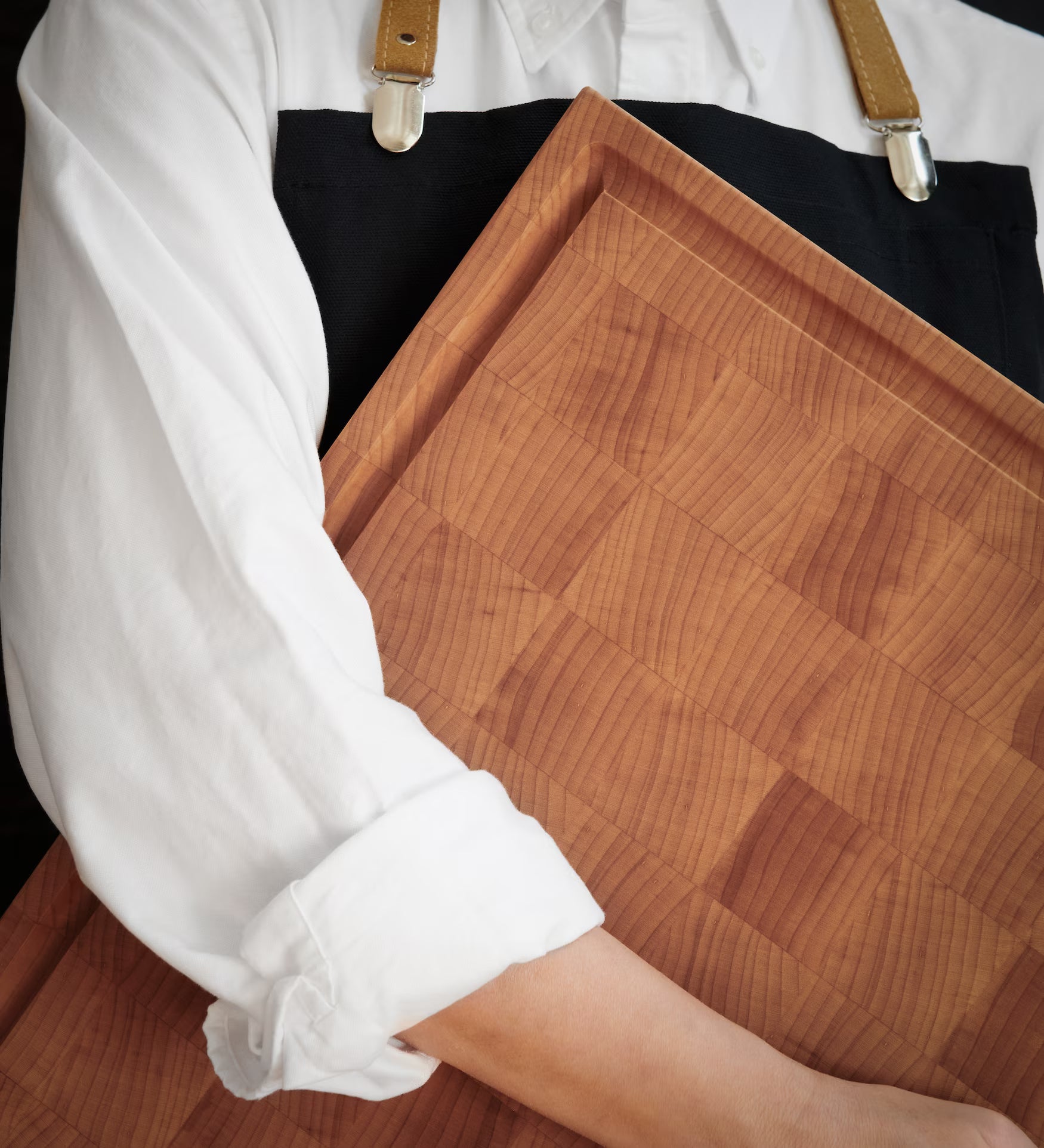 Artisan holding a Maison Liverani maple cutting board, highlighting fine grain and edge detail
