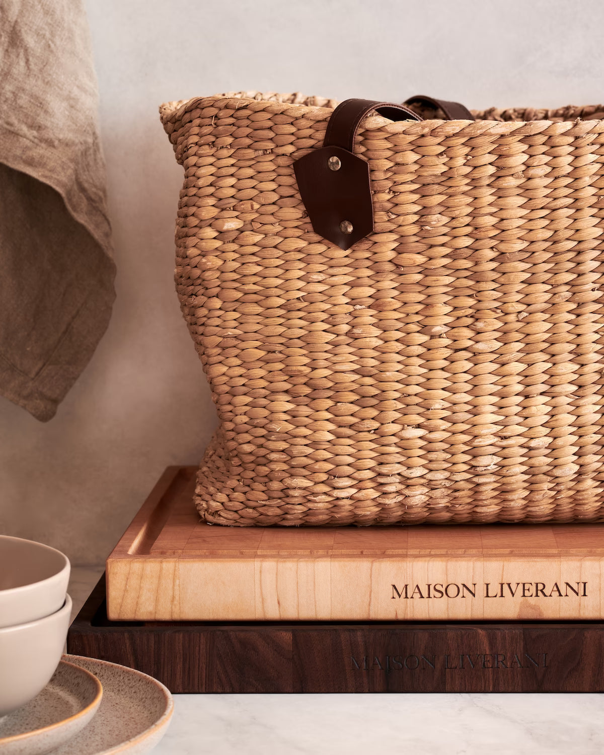 Maison Liverani jute bag resting atop stacked walnut and maple cutting boards
