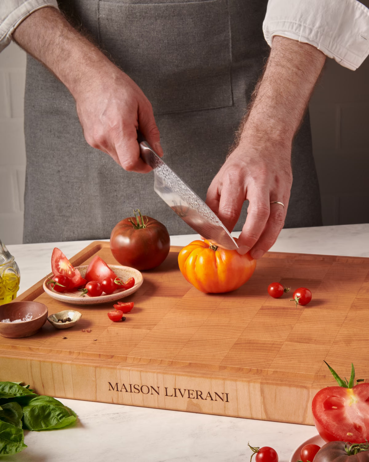 Chef slicing heirloom tomatoes on a maple Maison Liverani end-grain cutting board