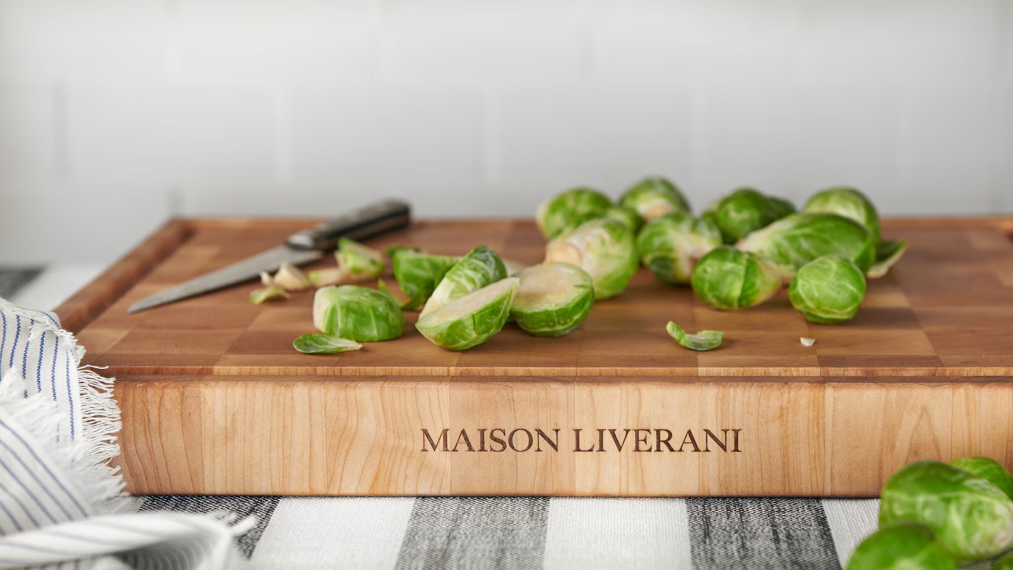 Maison Liverani name engraved on a maple end-grain cutting board with halved brussels sprouts