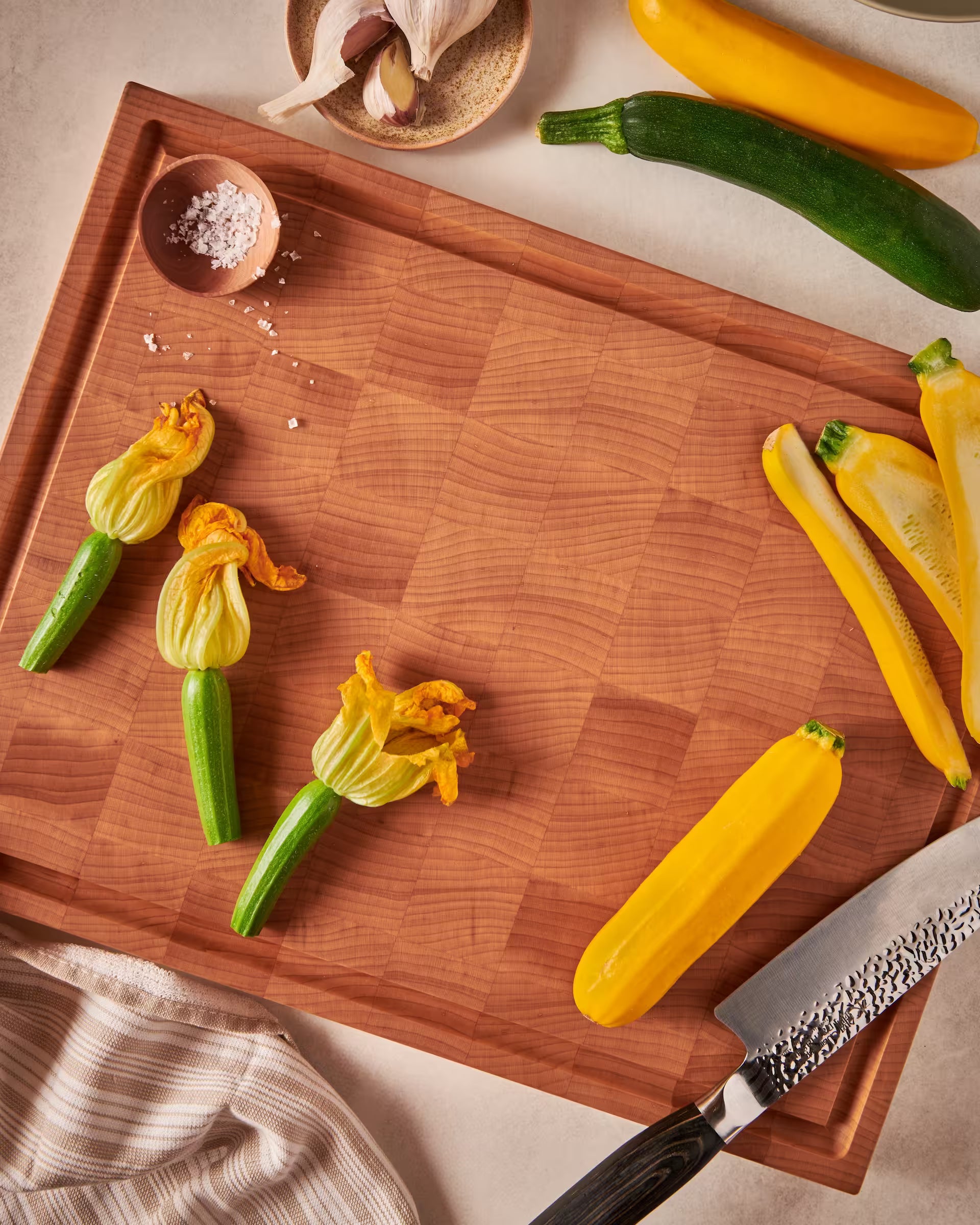Maple end-grain cutting board with zucchini blossoms and yellow and green squash
