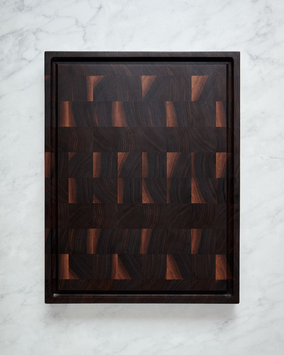 Maison Liverani walnut end-grain cutting board showing juice groove side on marble countertop