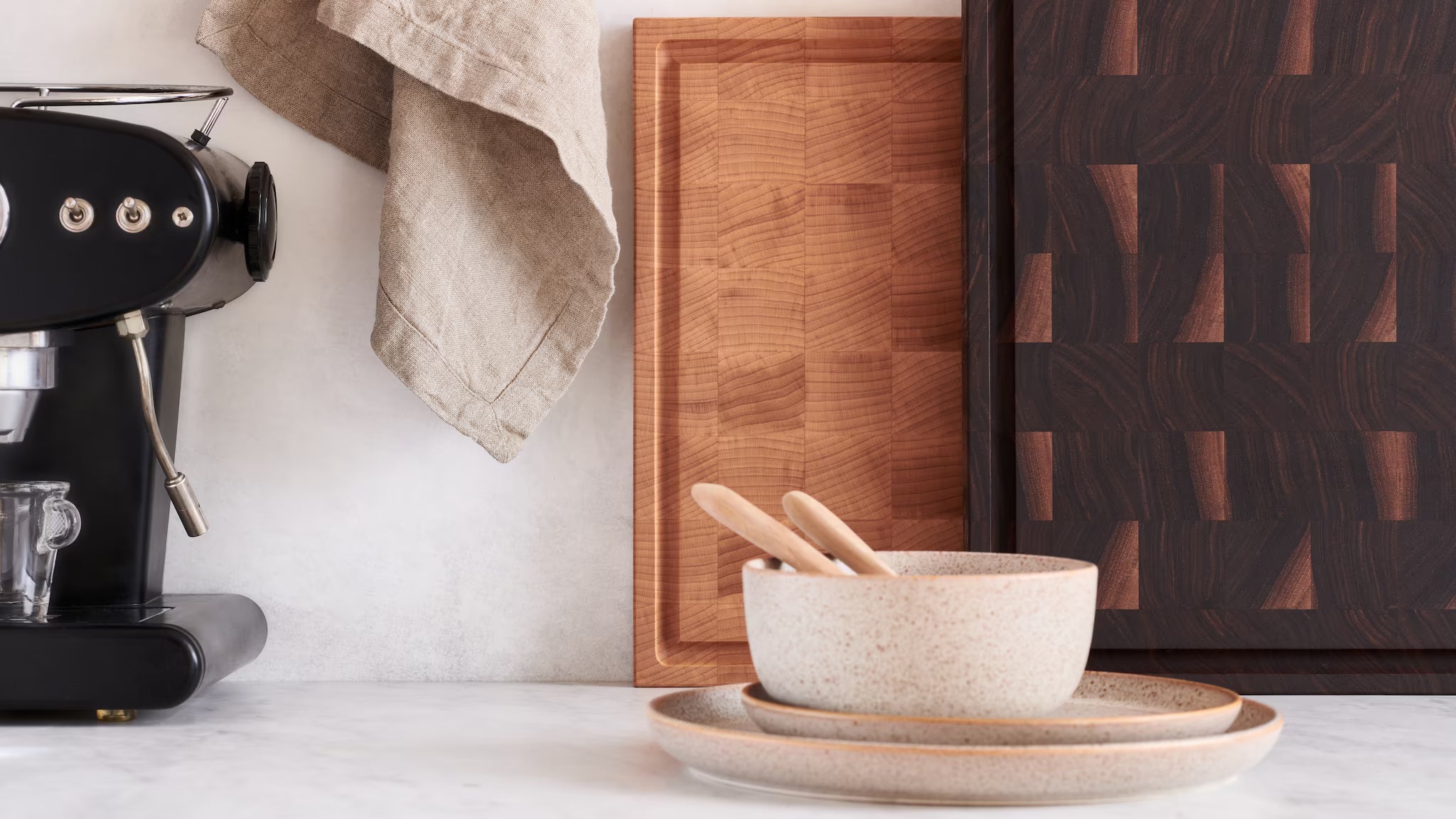 Maison Liverani walnut and maple end-grain cutting boards on a marble kitchen counter beside an espresso machine