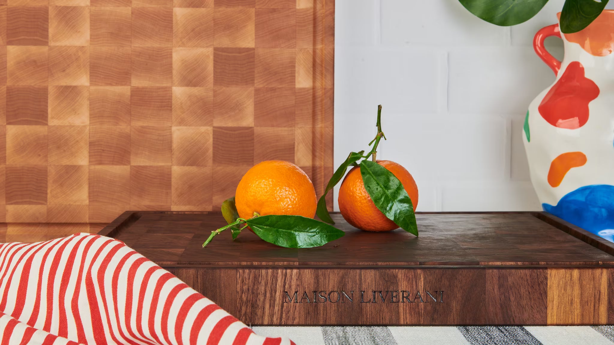 Maison Liverani walnut and maple end-grain cutting boards with whole oranges and the engraved brand name